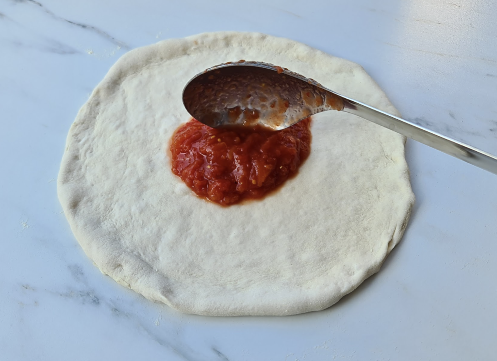 Spreading Neapolitan pizza sauce