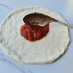 Spreading Neapolitan pizza sauce
