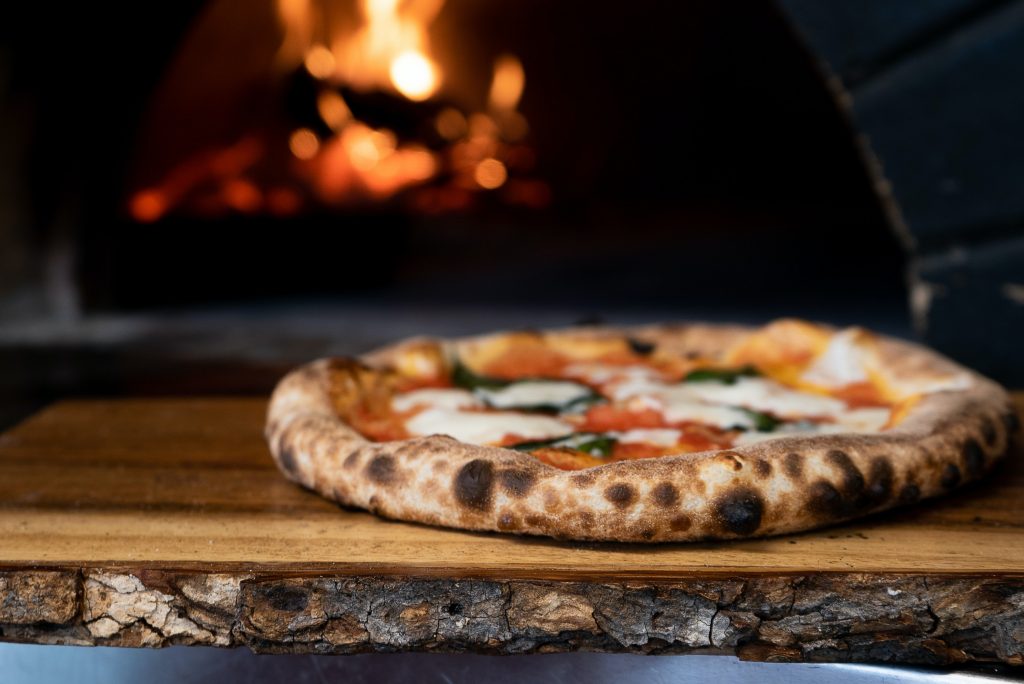 Neapolitan pizza in front of a wood-fired oven.