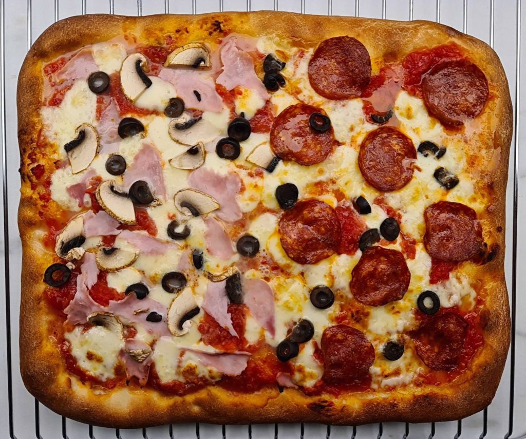 Thick-crust Sicilian pizza topped wiht salmi, ham, mushrooms and olives,