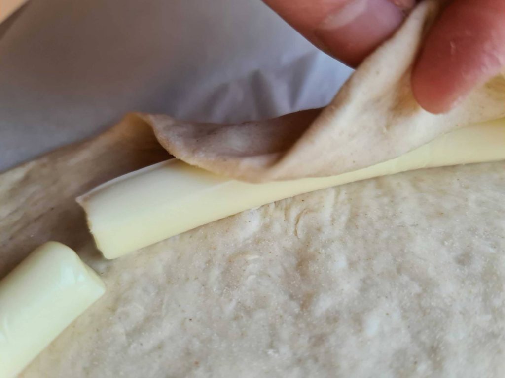Fold crust over cheese sticks