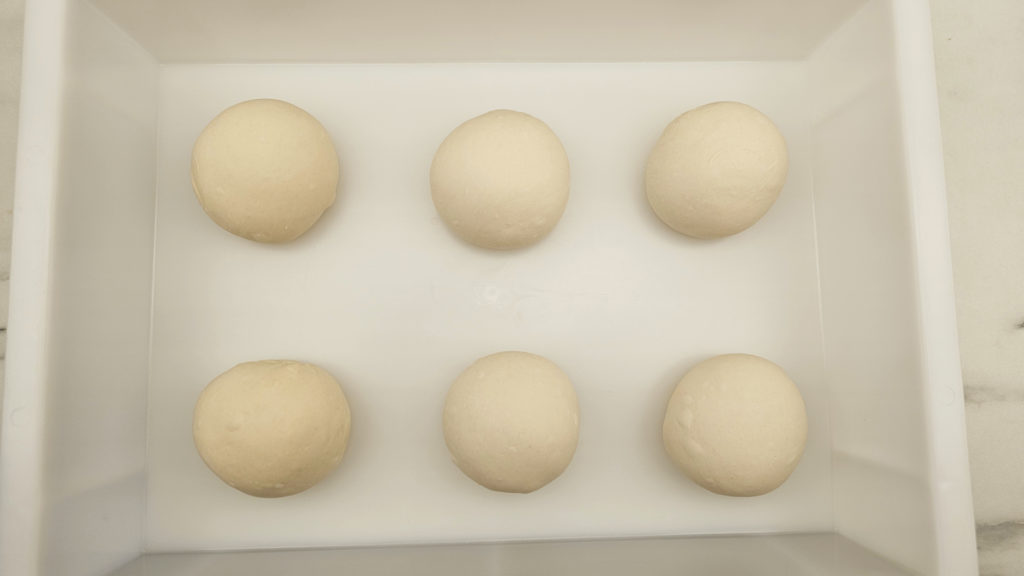 Six pizze dough balls in a proofing box